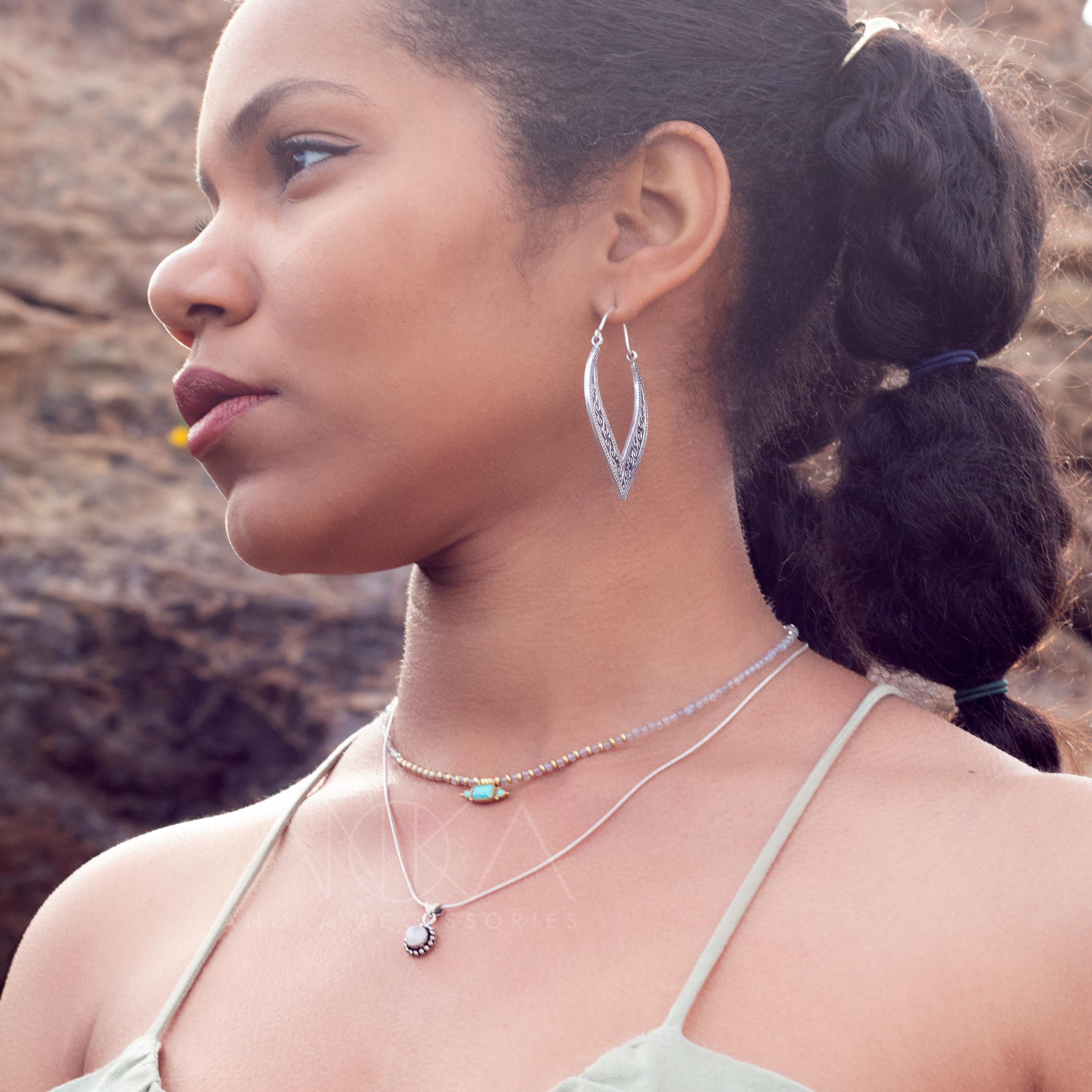 modelo con pendientes de aro plateados Anja y charm piedra lunar