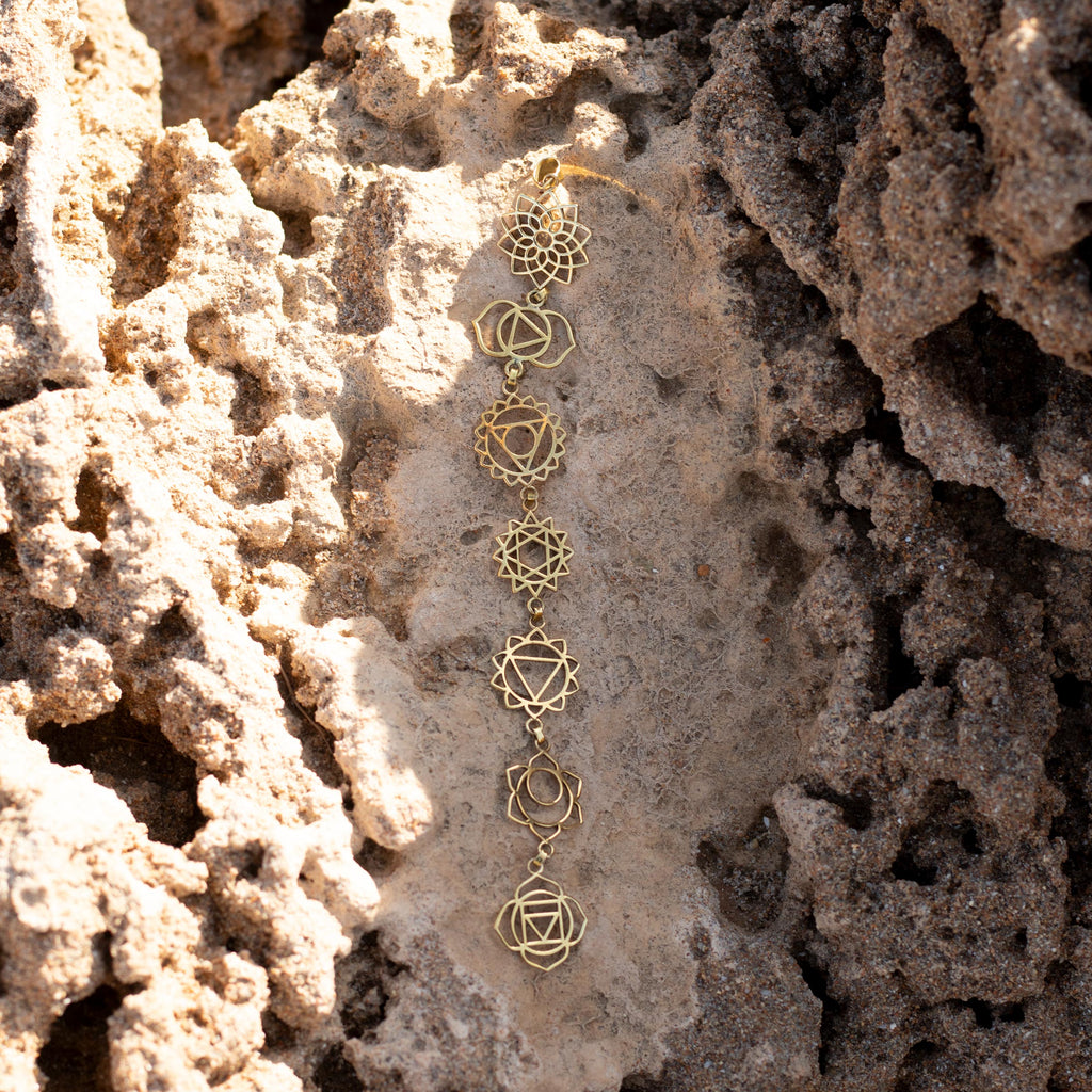 collar chakras dorado sobre piedra