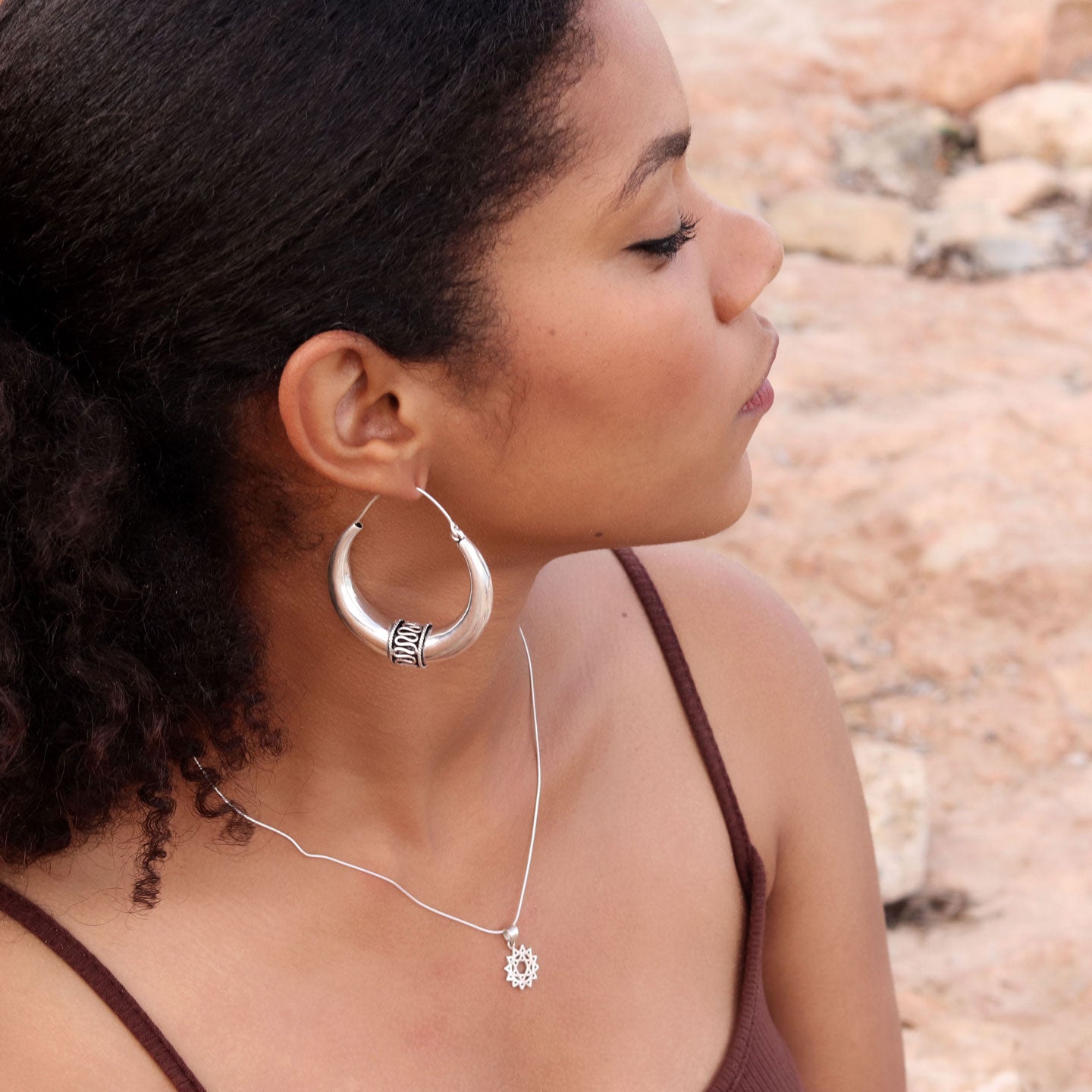 modelo con pendientes Naia aro plata y colgante chakra